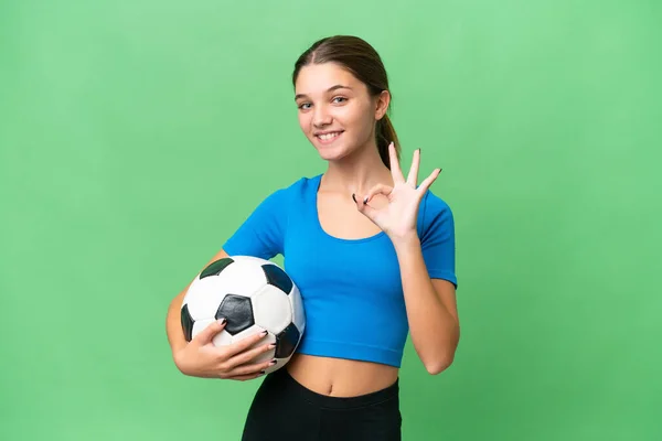 十几岁的白人女孩在与世隔绝的背景下踢足球 手指头显示出好的手势 — 图库照片