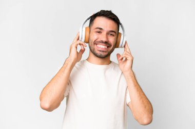 Young handsome caucasian man over isolated white background listening music