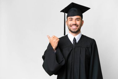 Young university graduate man over isolated white background pointing to the side to present a product