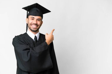 Young university graduate man over isolated white background pointing back