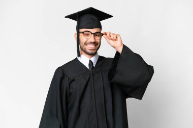 Young university graduate man over isolated white background with glasses and surprised