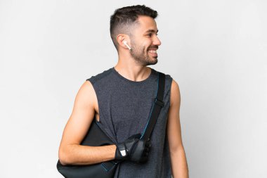 İzole edilmiş beyaz arka planda spor çantalı beyaz tenli genç adam.