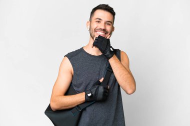İzole edilmiş beyaz arka planda spor çantalı beyaz bir adam gülümsüyor.