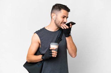 İzole edilmiş beyaz arka planda spor çantalı beyaz bir adam cep telefonuyla sohbet ediyor.