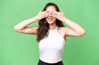 Kafkasyalı genç bir kadın izole edilmiş arka planda, gözleri elle kapatılmış.