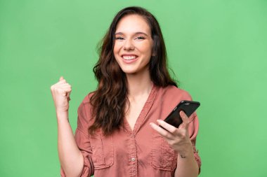 Kafkasyalı genç bir kadın cep telefonu kullanıyor ve zafer jesti yapıyor.