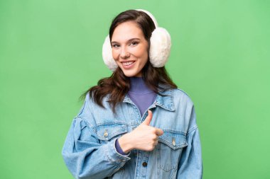 İzole edilmiş arka planda kışlık kuklalar takan beyaz bir kadın baş parmak işareti yapıyor.