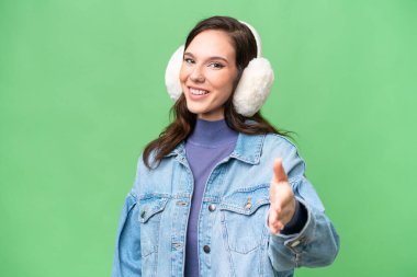 Kafkasyalı genç bir kadın izole edilmiş arka planda kışlık kuklalar takıyor ve iyi bir anlaşma için el sıkışıyor.