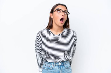 Beyaz arka planda izole edilmiş genç beyaz kadın yukarı bakıyor ve şaşırmış bir ifadeyle