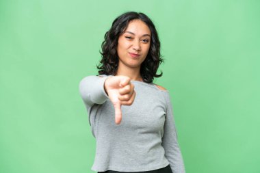 Arjantinli genç bir kadın izole edilmiş arka planda, olumsuz bir ifadeyle baş parmağını gösteriyor.