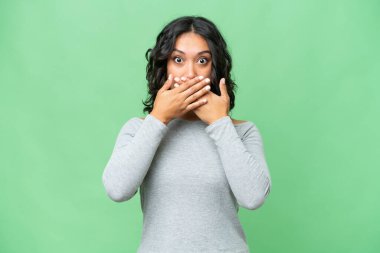 Arjantinli genç bir kadın izole edilmiş arka planda ağzı elleriyle kapatıyor.