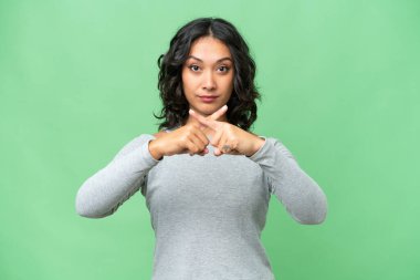 Arjantinli genç bir kadın izole edilmiş arka planda sessizlik işareti gösteriyor.