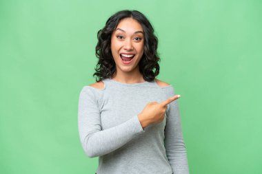 Arjantinli genç bir kadın izole edilmiş arka planda şaşırmış ve işaret ediyor.