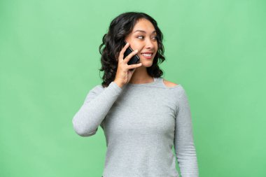 Arjantinli genç bir kadın izole edilmiş bir arka planda cep telefonuyla sohbet ediyor.