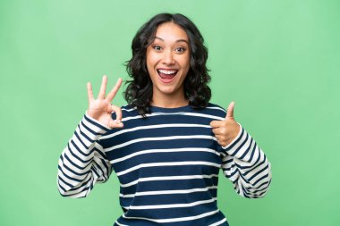 Arjantinli genç bir kadın izole edilmiş arka planda işaret ve baş parmak hareketi gösteriyor.