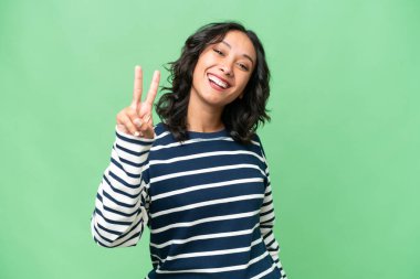 Arjantinli genç bir kadın izole edilmiş arka planda gülümsüyor ve zafer işareti gösteriyor.