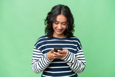 Arjantinli genç bir kadın izole edilmiş arka planda cep telefonuyla mesaj gönderiyor.