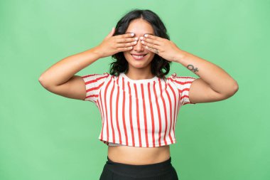 Arjantinli genç bir kadın izole edilmiş arka planda gözlerini elleriyle kapatıyor.