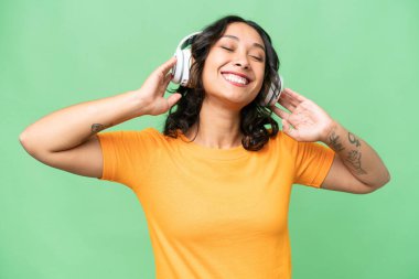 Arjantinli genç bir kadın izole edilmiş arka planda müzik dinliyor ve şarkı söylüyor.