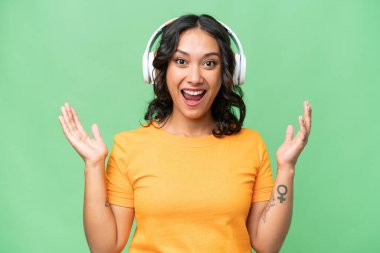 Arjantinli genç kadın izole edilmiş arka planda şaşırmış ve müzik dinliyor.