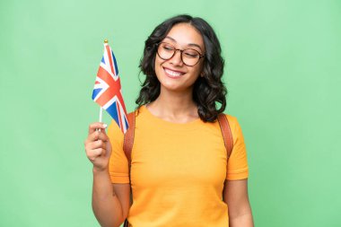 Arjantinli genç bir kadın Birleşik Krallık bayrağını mutlu bir ifadeyle izole edilmiş arka planda tutuyor.