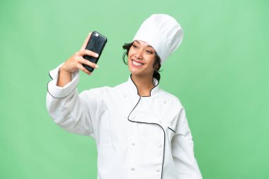 Genç aşçı Arjantinli kadın izole bir arkaplanda selfie çekiyor.