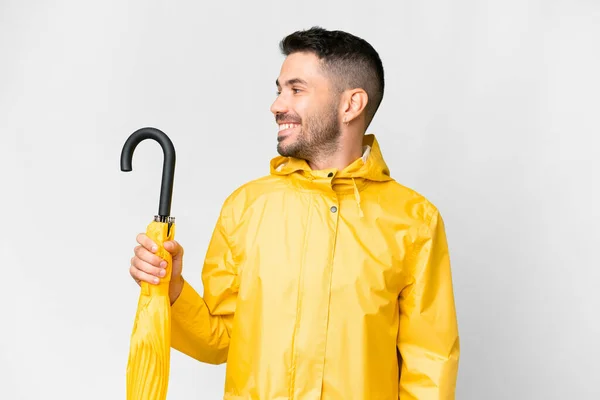 年轻的高加索人 身穿防雨外套 头戴雨伞 环绕着孤独的白色背景 — 图库照片