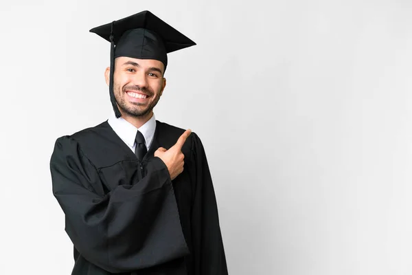 Fiatal Egyetemi Diplomás Férfi Elszigetelt Fehér Háttér Mutatva Oldalon Hogy — Stock Fotó