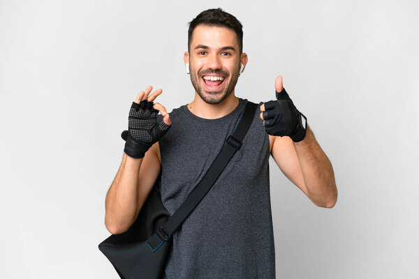 Young sport caucasian man with sport bag over over isolated white background showing ok sign and thumb up gesture