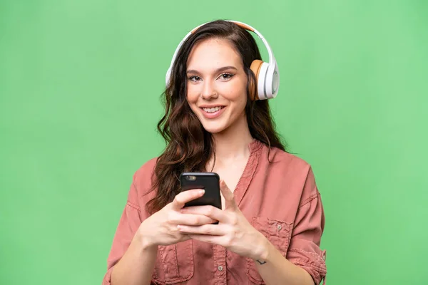 Young Caucasian Woman Isolated Background Listening Music Mobile Looking Front — Stock Photo, Image