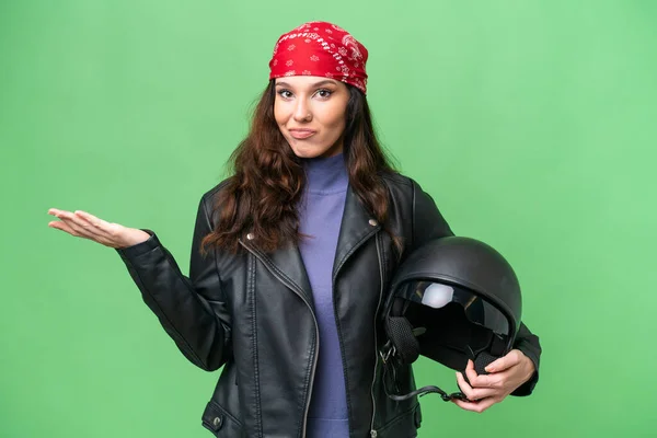 若いですCaucasian女性とともにオートバイヘルメット上の隔離された背景持っています疑問ながら手を上げます — ストック写真