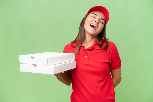 ピザ配達Caucasian女性ともに仕事の制服ピザボックスを拾う隔離された緑のクロマの背景笑い — ストック写真