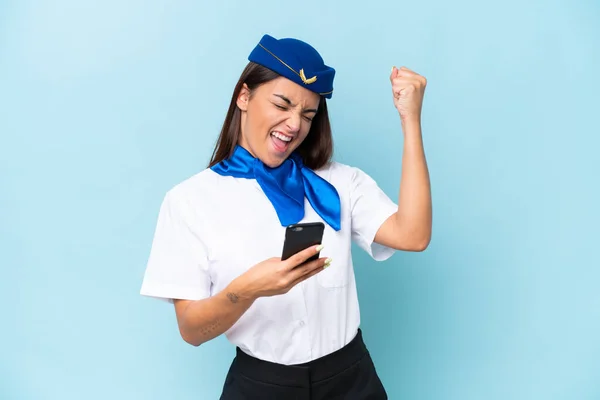 飛行機スチュワーデスCaucasian女性隔離上の青の背景に電話で勝利位置 — ストック写真