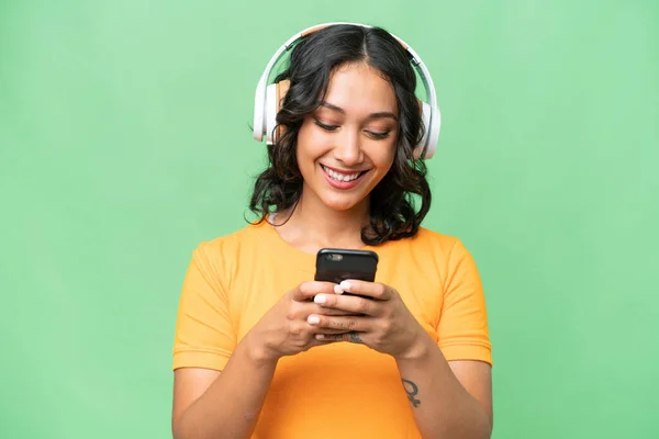Giovane Donna Argentina Caucasica Sfondo Isolato Ascoltando Musica Guardando Cellulare — Foto Stock