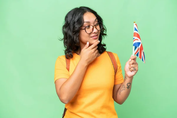 Mladá Argentinská Žena Držící Britskou Vlajku Nad Izolovaným Pozadím Přemýšlející — Stock fotografie