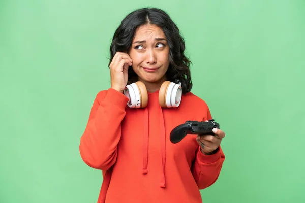 年轻的阿根廷女人在孤立的背景下与电子游戏控制器玩耍时感到沮丧 并捂住耳朵 — 图库照片
