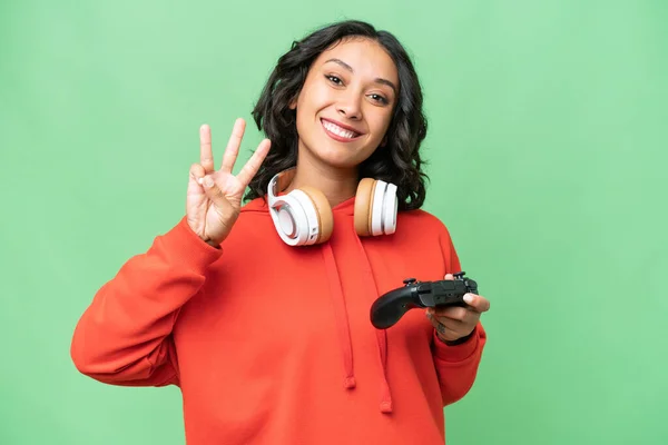 年轻的阿根廷女人快乐地和一个视频游戏控制器一起在孤立的背景下玩耍 用手指数着三个 — 图库照片