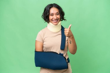 Arjantinli genç bir kadın boyunluk takıyor ve izole bir arka planda baş parmağıyla asılı duruyor. Çünkü iyi bir şey oldu.