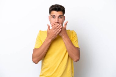 Beyaz arka planda izole edilmiş genç beyaz bir adam elleriyle ağzını kapatıyor.