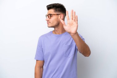 Beyaz arka planda izole edilmiş genç beyaz adam dur hareketi yapıyor ve hayal kırıklığına uğruyor.