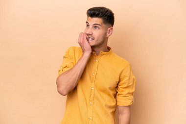 Young caucasian man isolated on beige background is a little bit nervous