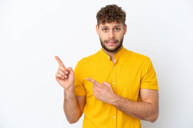 Beyaz arka planda izole edilmiş genç, yakışıklı, beyaz bir adam. Korkmuş ve kenarı işaret ediyor.