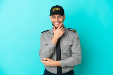 Mavi arka planda sırıtan genç bir güvenlik görevlisi.