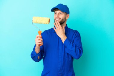 Ressam beyaz adam mavi arka planda izole edilmiş gülümserken yukarı bakıyor.