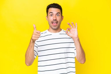 Soyutlanmış sarı arka planda genç yakışıklı adam işaret ve işaret gösteriyor.