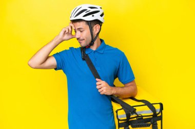 Termal sırt çantalı yakışıklı genç adam izole edilmiş sarı arka planda gülüyor.