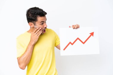 İzole edilmiş beyaz arka plan üzerinde genç yakışıklı bir adam elinde büyüyen bir istatistik oku sembolü ve şaşırmış yüz ifadesi olan bir tabela tutuyor.