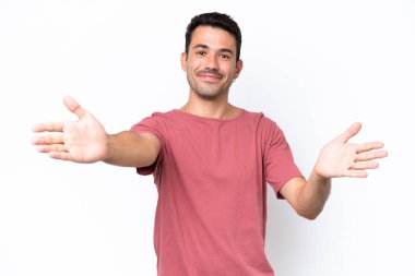 Genç yakışıklı, soyutlanmış beyaz bir arka plan sunuyor ve davet ediyor.