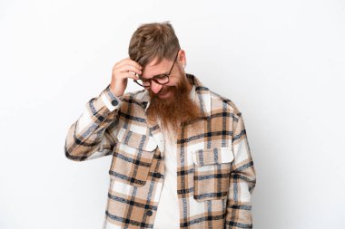 Kızıl saçlı uzun sakallı adam beyaz arka planda yalnız gülüyor.