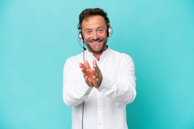 Telemarketer caucasian man working with a headset isolated on blue background applauding after presentation in a conference